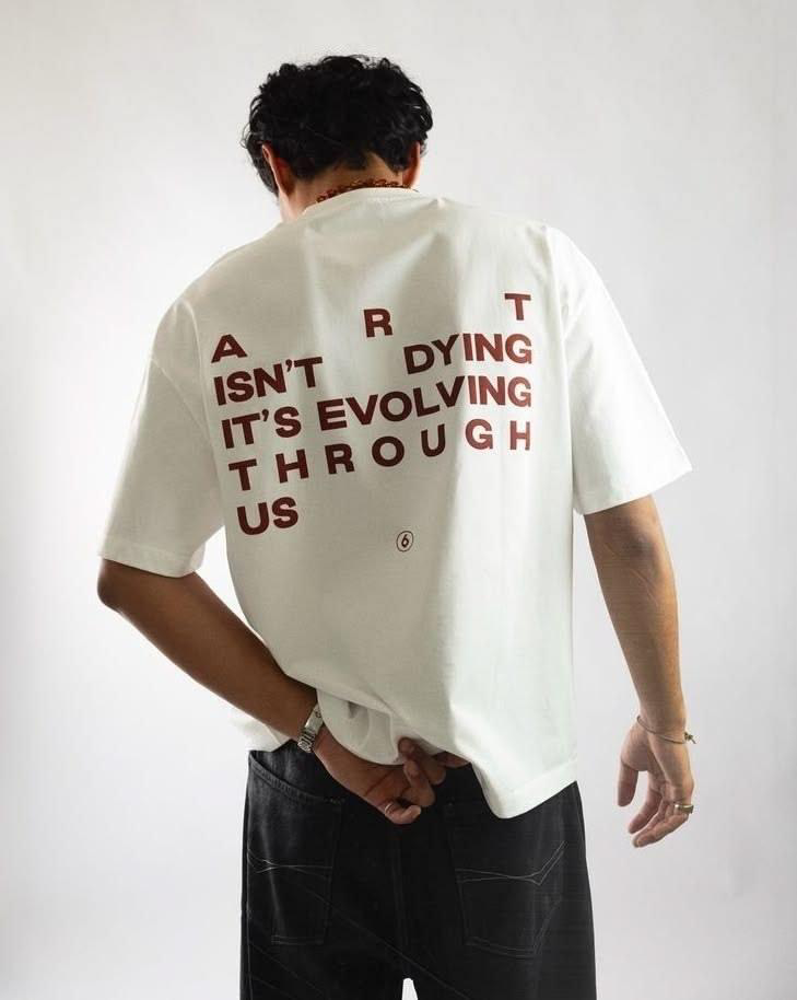 Off white relaxed tee with maroon scattered type reading Art is not dying, it is evolving through us